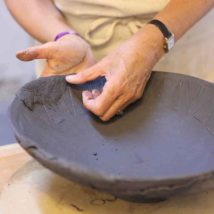 Image of a woman molding the pot together